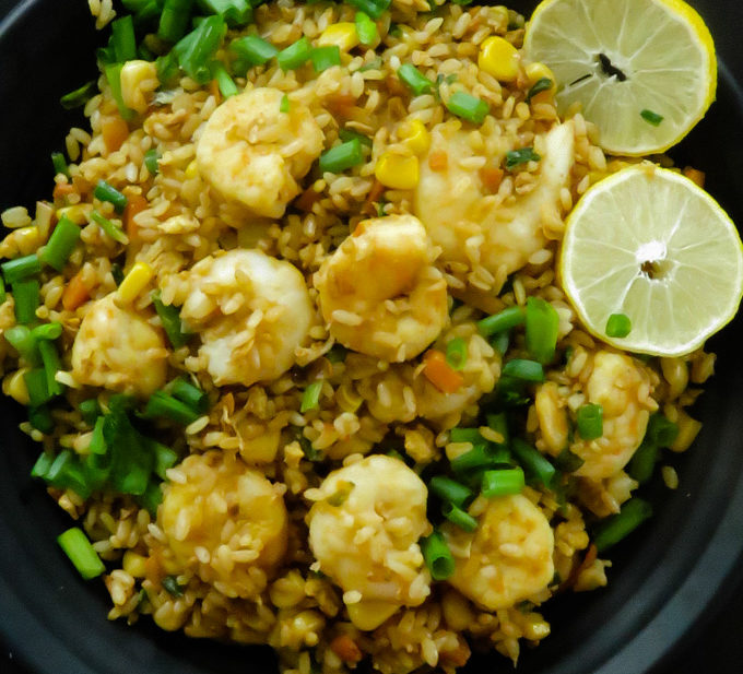 tasty shrimp fried rice served with lime on a plate.