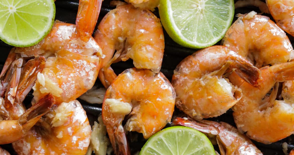 a tray of peel and eat shrimp with lime wedges
