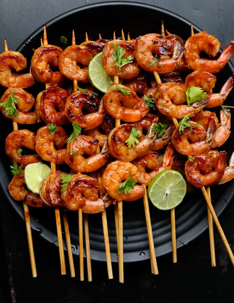 grilled shrimp in skewers with lime wedges