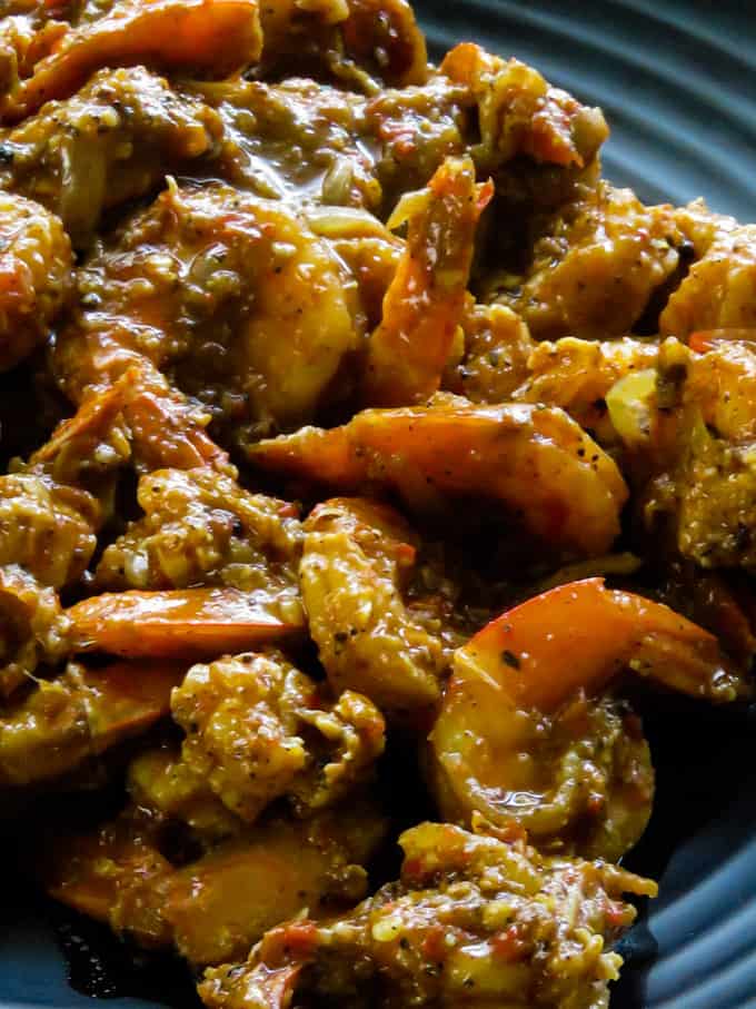 Shrimp vindaloo curry on a black plate.