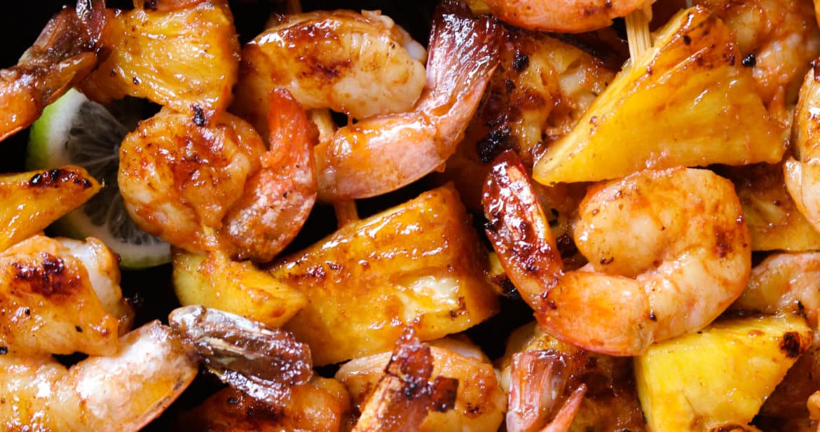 pineapple shrimp skewers with lime wedges..