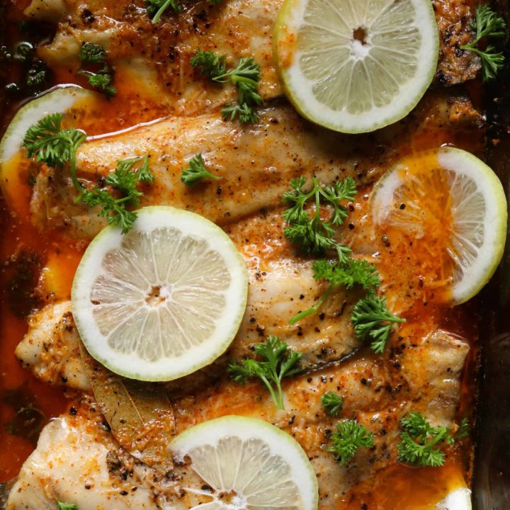 baked tilapia garnished with lemon and parsley.
