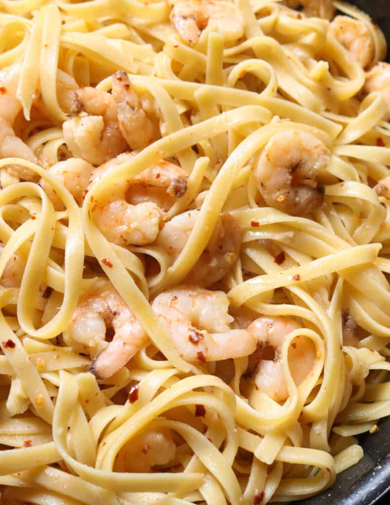 tossing the shrimp with the pasta.
