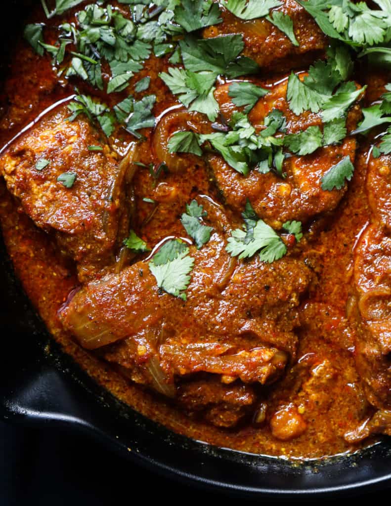 goan fish curry served in a bowl with chopped coriander leaves as garnish.