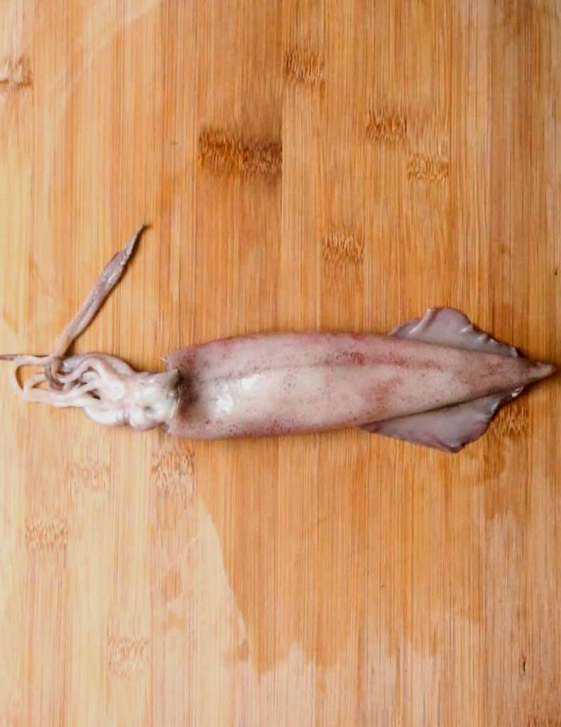 a squid placed on a chopping board ready to be cleaned.