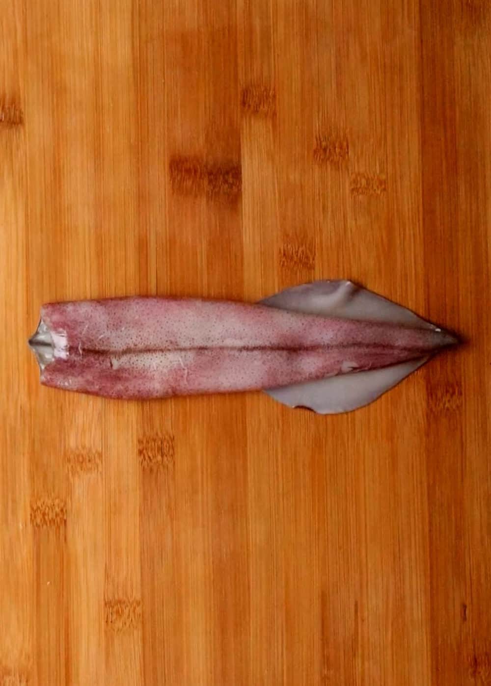 image of a squid to clean on a wooden chopping board.