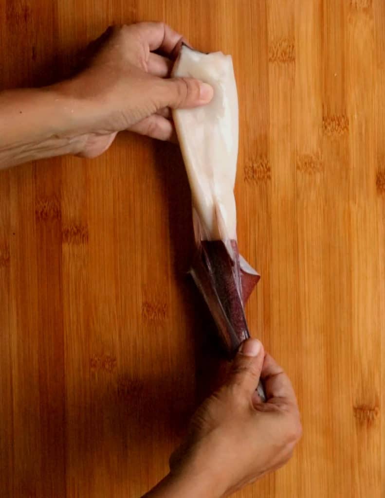 peeling the outer skin of the squid from the top to the bottom.