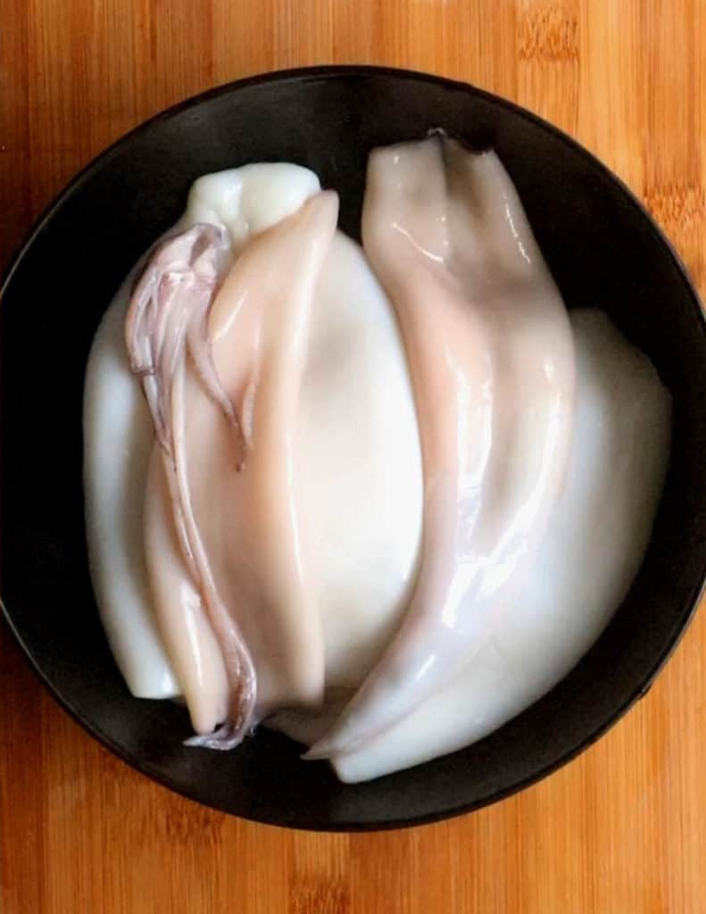 cleaned squid in a black bowl. ready to cook.